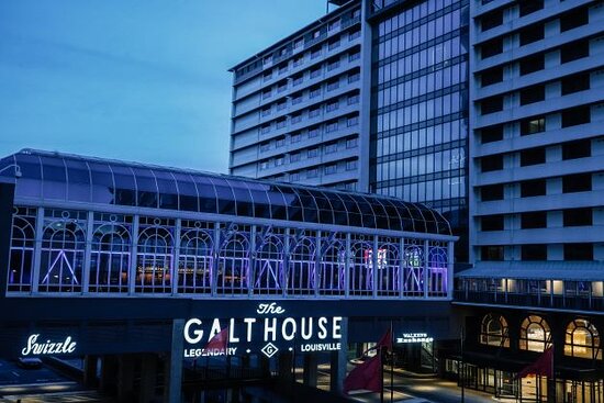 The Galt House Hotel at dusk, its marquee and glass Conservatory lit in blue